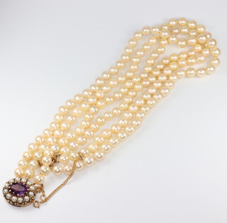 A triple strand cultured pearl necklace with a 9ct yellow gold amethyst and seed pearl clasp 43cm, the amethyst 14mm x 7mm, pearls approx. 7mm diam. 