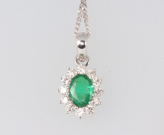 A white metal oval emerald and diamond pendant 18mm, the emerald approx. 0.7ct, the brilliant cut diamonds approx. 0.4ct, 3 grams, on a 44cm silver chain 