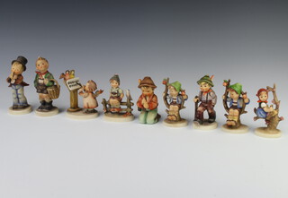 A collection of 9 Hummel figures comprising boy with basket 13cm S13/0, boy in a tree 142 3/0 10cm, girl in a tree 147 3/0 10m, kneeling boy 116 3/0 10cm, boy in a tree 742 3/0 10cm, boy playing a recorder 55 3/0 11cm, grandpa's boy 562 10cm, boy sitting on a stile 10cm and angel standing at a lectern 169 11cm 