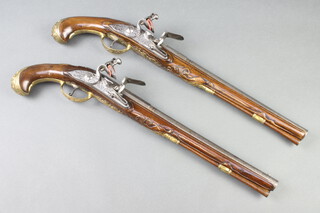 Johann Jacob Behr, a handsome pair of Dutch early 18th Century flintlock holster pistols, the 35cm Damascus barrels inlaid huntsman, hound and deer, the engraved locks signed I.I Behr, the heavily carved walnut stocks with gilt bronze butt caps decorated grotesques, the trigger guard with winged cherub, the side plates in the form of mythical beasts and the escutcheons with portrait busts of a Queen surmounted by a crown, 50cm overall 