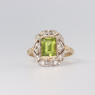 An Edwardian style yellow metal peridot and diamond ring, the emerald cut stone 1.6ct, the brilliant cut diamonds 0.4ct, size N, 3.2 grams 