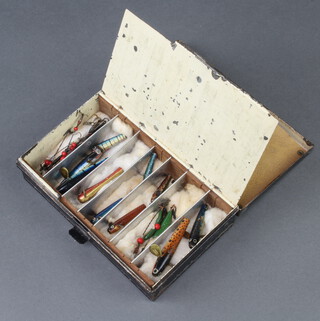 A black Japanned lure box containing various fishing lures 