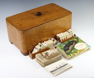 A rectangular box containing a small collection of black and white and coloured postcards including liners and various Brooke Bond tea cards 