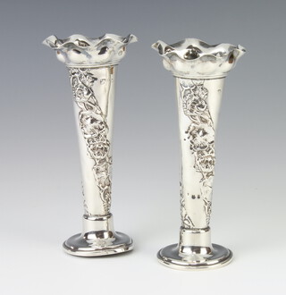 A pair of Edwardian tapered repousse silver posy vases decorated with flowers, 14cm, 105 grams (marks rubbed) 
