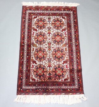 A white, brown and red Persian rug with 8 stylised medallions to the centre within a multi row border 180cm x 113cm 