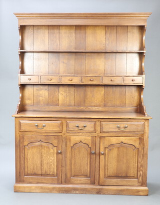 A 17th Century style oak dresser, the upper section with moulded cornice, fitted a shelf above 6 spice drawers, the base fitted 3 drawers above 3 arched panelled doors 203cm h x 152cm w x 46cm, d 