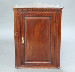 A Georgian mahogany hanging corner cabinet with moulded and dentilled cornice enclosed by a panelled door 92cm h x 72cm w x 41cm d (complete with key) 