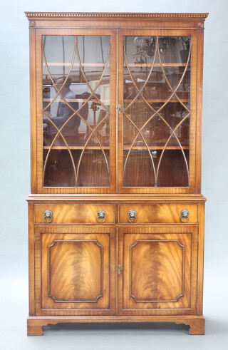 A 20th Century Georgian style mahogany display cabinet on cabinet with moulded and dentil cornice, fitted adjustable shelves enclosed by astragal glazed panelled doors, the base fitted 2 drawers with lion ring mask handles above a pair of panelled doors, raised on bracket feet 206cm h x 115cm w x 40cm d 
