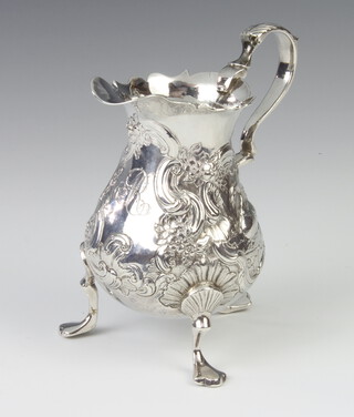 A Georgian repousse silver cream jug decorated with birds and engraved monogram, raised on trefid feet, rubbed marks, 9cm, 104 grams