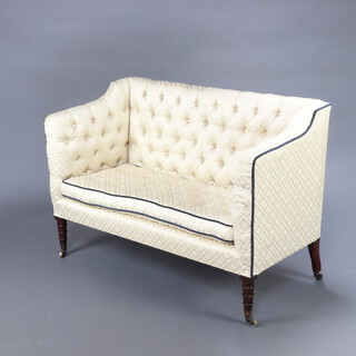 A William IV 2 seat sofa upholstered in cream buttoned material raised on turned supports, brass caps and casters 76cm h x 111cm w x 51cm d (seat 89cm x 37cm)  