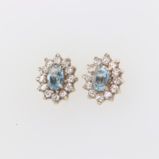 A pair of yellow metal oval topaz and diamond ear studs, the centre stone each 0.50 each surrounded by 12 brilliant cut diamonds each 0.03ct 12mm x 10mm, 2.6 grams 