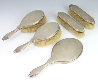 A silver dressing table set comprising hand mirror, 2 hair brushes, 2 clothes brushes with engine turned decoration London 1913 