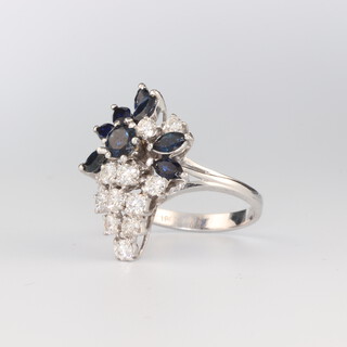 A white metal stamped 18ct sapphire and diamond cocktail ring with 12 brilliant cut diamonds approx. 0.07ct each and 7 oval cut sapphires approx. 1ct and a brilliant cut sapphire approx. 0.03ct, size P, 7.3 grams 