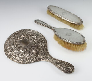 A silver backed hair brush and clothes brush Birmingham 1916, an Edwardian repousse hand mirror (holed) Birmingham 1908  