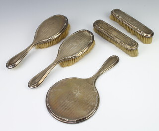 A 5 piece silver backed dressing table set comprising hand mirror, 2 hair brushes, 2 clothes brushes, Birmingham 1923  
