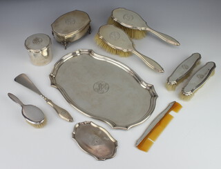 A silver dressing table set comprising quatrefoil tray 34cm, a ditto pin tray 14cm, a trinket box raised on scroll legs 14cm, a circular box and cover 7.5cm, 2 hair brushes, 2 clothes brushes, a shoe horn and comb, all engraved with the monogram RS together with a babies brush 984 grams weighable silver