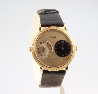 A gentleman's yellow metal double dial Piaget wristwatch with gilt and black dials and an engine turned face in a 35mm case, on a distressed leather bracelet with a yellow metal stamped 750 clasp numbered 612104.317700  