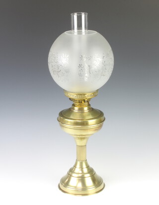 A gilt metal oil lamp with clear glass chimney and etched glass shade, raised on a reeded column 56cm h x 15cm 
