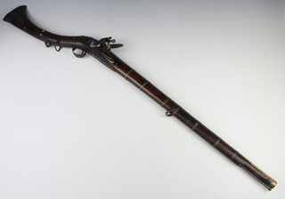An 18th Century Moghul flintlock carbine rifle with 65cm octagonal Koftgari gold inlaid Damascus steel barrel, the steel lock with East India Company engraved mark, the carved walnut stock inlaid mother of pearl, complete with steel ramrod, 101cm overall  