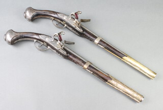 A near pair of 18th Century ottoman flintlock long holster pistols, the 35cm circular steel barrels heavily engraved and marked 13 and 14, with steel locks also heavily engraved throughout and trigger guards, both with carved walnut long eared steel clad butts 53cm overall 