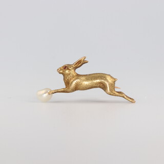A yellow metal bar brooch in the form of a hare with a ruby eye chasing a baroque pearl 4.5 grams, 30mm 