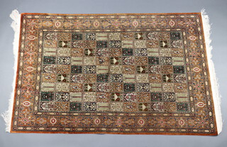 A North West Persian brown and green ground silk carpet, the central field having 66 rectangular panels with floral motifs 201cm x 133cm 
