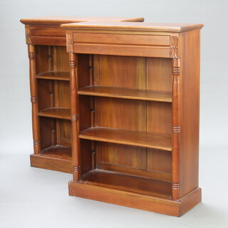 A pair of Victorian style hardwood open bookcases with adjustable shelves, the upper sections fitted a secret drawer flanked by columns, raised on a platform base 123cm h x 94cm w x 34cm d 