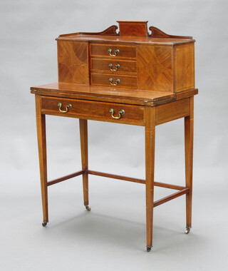 An Edwardian inlaid mahogany writing table, the upper section with shaped back fitted 3 drawers flanked by cupboards enclosed by panelled doors, the base fitted a drawer, raised on square tapered supports ending in brass caps and casters 108cm h x 76cm w x 40cm d 