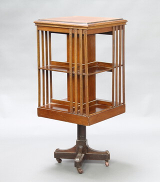 An Edwardian square oak revolving bookcase raised on a cruciform base 105cm h x 47cm w x 47cm d 