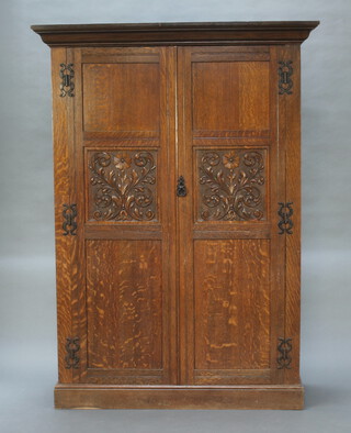 A 19th Century Continental carved oak wardrobe with moulded cornice enclosed by panelled doors with iron H shaped hinges, 191cm h x 138cm w x 54cm d 