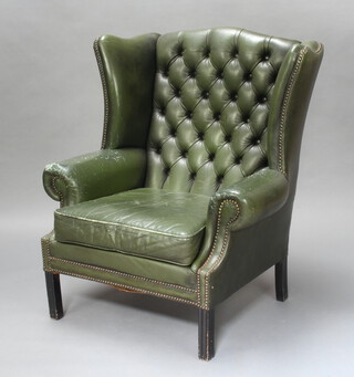 A Georgian style winged armchair upholstered in green leather, raised on square supports 104cm h x 86cm w x 66cm d (seat 45cm x 47cm, leather is scuffed and damaged in places)  