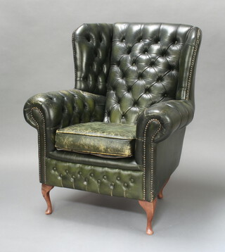 A Georgian style winged armchair upholstered in green buttoned leather, raised on cabriole supports 104cm h x 88cm w x 76cm d (seat 35cm x 45cm, leather is scuffed, the back legs have been replaced)