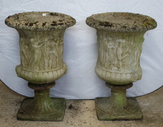 A pair of well weathered concrete garden urns decorated classical figures, raised on a square base 91cm h x 65cm diam. (in 2 sections) 