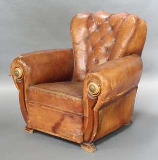 A 1930's Art Deco shaped armchair upholstered in brown buttoned leather 87cm h x 94cm w x 79cm d (seat 33cm w x 39cm d)