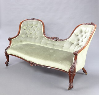 A Victorian carved walnut showframe double spoon back settee upholstered in green material, raised on carved cabriole supports 92cm h x 170cm w x 68cm d (seat 127cm x 37cm) 