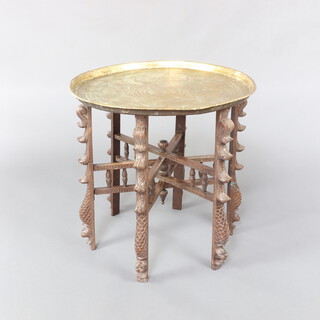 An Indian circular engraved Benares brass tray raised on a folding carved hardwood stand 59cm h x 58cm diam. 
