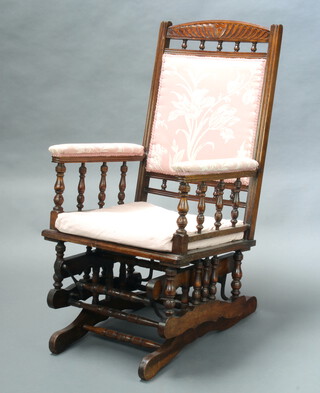 A 19th Century American carved walnut rocking chair, the seat and arms upholstered in pink floral material with bobbin turned decoration 116cm h x 58cm w x 52cm d  