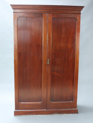 A Victorian mahogany wardrobe with moulded cornice enclosed by panelled doors, raised on a platform base 208cm h x 132cm w x 56cm d 
