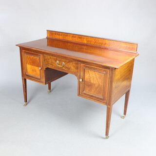 An Edwardian inlaid mahogany writing/dressing table with raised back fitted a drawer flanked by cupboards, raised on square tapered supports, brass caps and casters 89cm h x 124cm w x 53cm d 