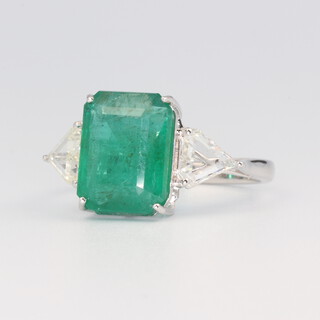 A white metal stamped 18k emerald and diamond ring, the rectangular cut centre stone approx. 4.58ct, the 2 triangular cut diamonds 0.6ct, 3.7 grams, size N 