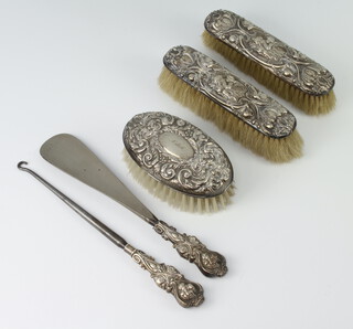 A silver backed hairbrush Birmingham 1975, 2 other mounted clothes brushes, a silver button hook and shoe horn 