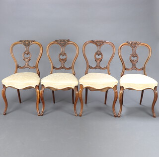 A set of 4 Victorian walnut balloon back chairs with carved splats and overstuffed seats raised on French cabriole supports 87cm h x 45cm w x 40cm d (seat 21cm x 28cm)