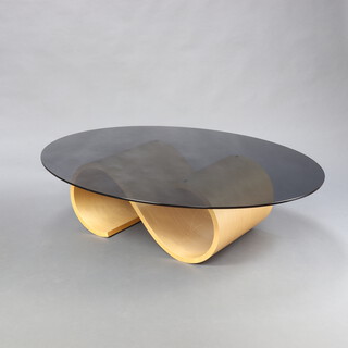 A Mid-Century S shaped plywood base and oval smoked plate glass topped coffee table 40cm h x 118cm x 150cm  