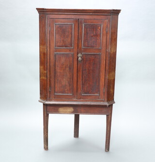 A 19th Century oak hanging corner cabinet with moulded cornice, fitted shelves enclosed by panelled doors raised on an associated base 139cm h x 77cm w x 54cm d 