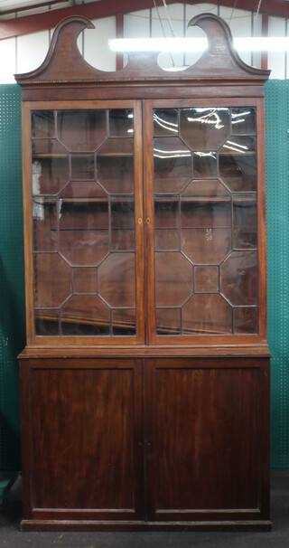A Georgian mahogany bookcase on cabinet with shaped cornice, fitted adjustable shelves enclosed by astragal glazed panelled doors, base enclosed by panelled doors 100cm h x 122cm w x 54cm d (contact marks and scratches in places, crack to pane of glass, section of inlay missing to the cornice)
