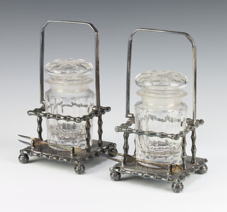 A pair of Edwardian cut glass pickle jars and covers on a pair of silver plated bamboo effect stands with forks 