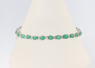 A white metal emerald and diamond tennis bracelet comprising graduated emeralds 8.95ct and brilliant cut diamonds 0.6ct, 18cm, 8.4 grams 