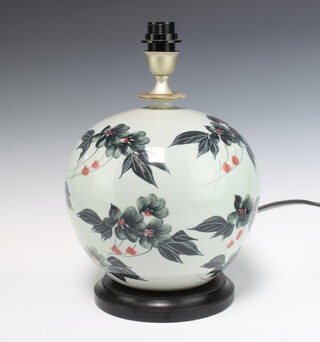 A contemporary cylindrical table lamp decorated with stylised flowers, raised on a wooden socle 30cm 