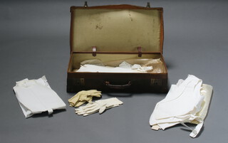 A brown leather suitcase with P&O SS Mongol label 15cm h x 66cm w x 36cm d, containing 2 stiff fronted dress shirts, 3 Marcella waistcoats, 3 pairs of mens white leather gloves and a pair of cotton gloves 