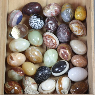 29 carved hardstone and other model eggs, contained in a wooden crate 
